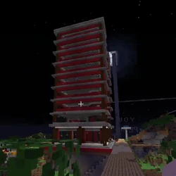 A screenshot from someone's stream. It shows the hotel standing on an offshoot to the Prime Path. It stands at nine stories tall, each floor an exact replica of the last. The hotel is made out of spruce logs, red concrete, and stone bricks. In the screenshot, it stands empty, the moon rising behind it.