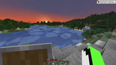 A screenshot from one of Dream's Dsmp streams showing off the space where the community house would eventually be built. It's a Minecraft landscape of a large lake surrounded by trees on the shoreline. The sun is setting in the screenshot. Dream holds a shield in his offhand.